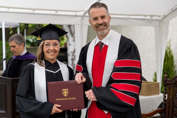 Student and Neil Fassina, ϲʿѯ President, both holding a parchment folder at a convocation ceremony